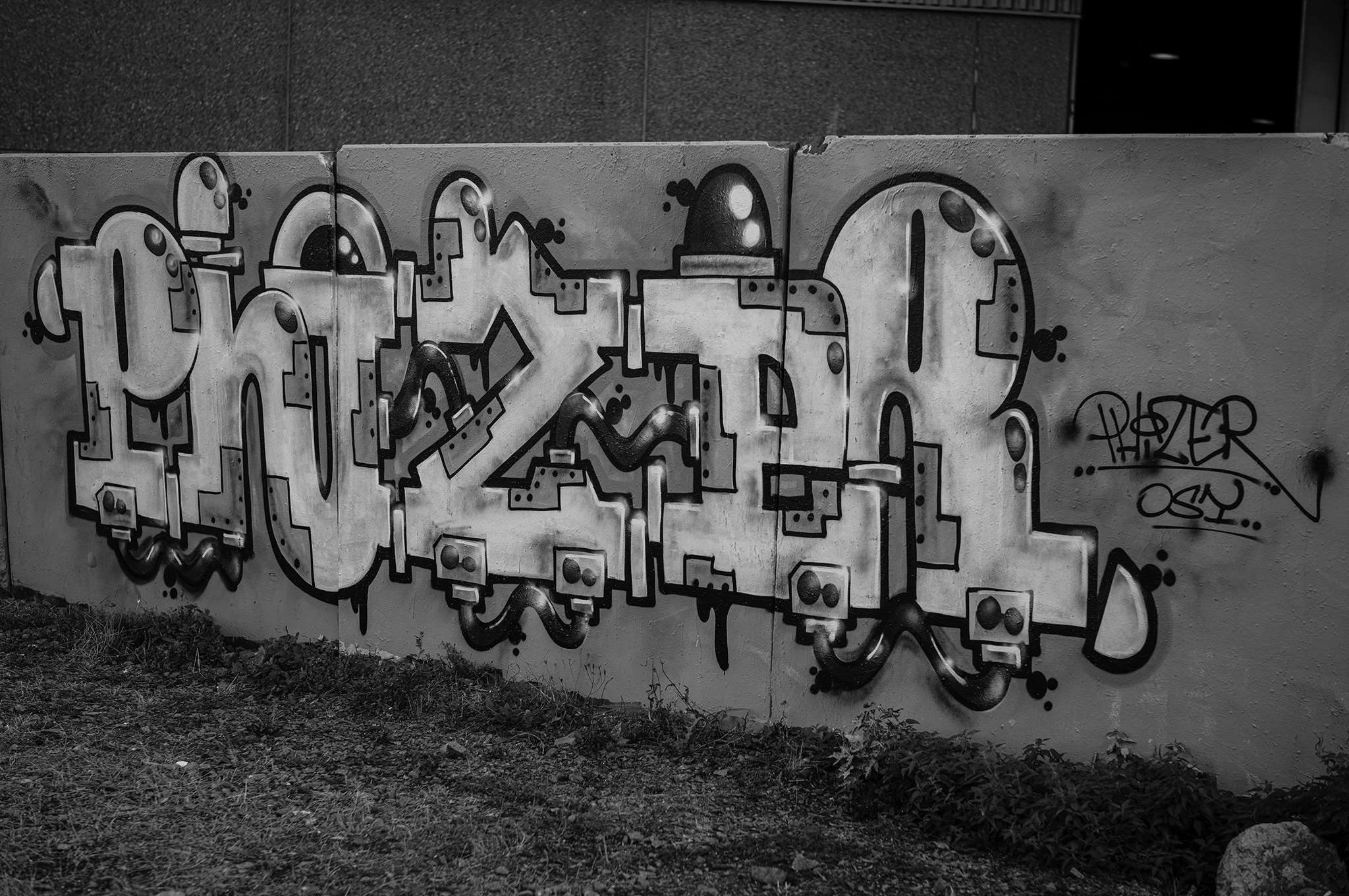 Large graffiti piece with rounded letters and heavy black outlines on a concrete wall